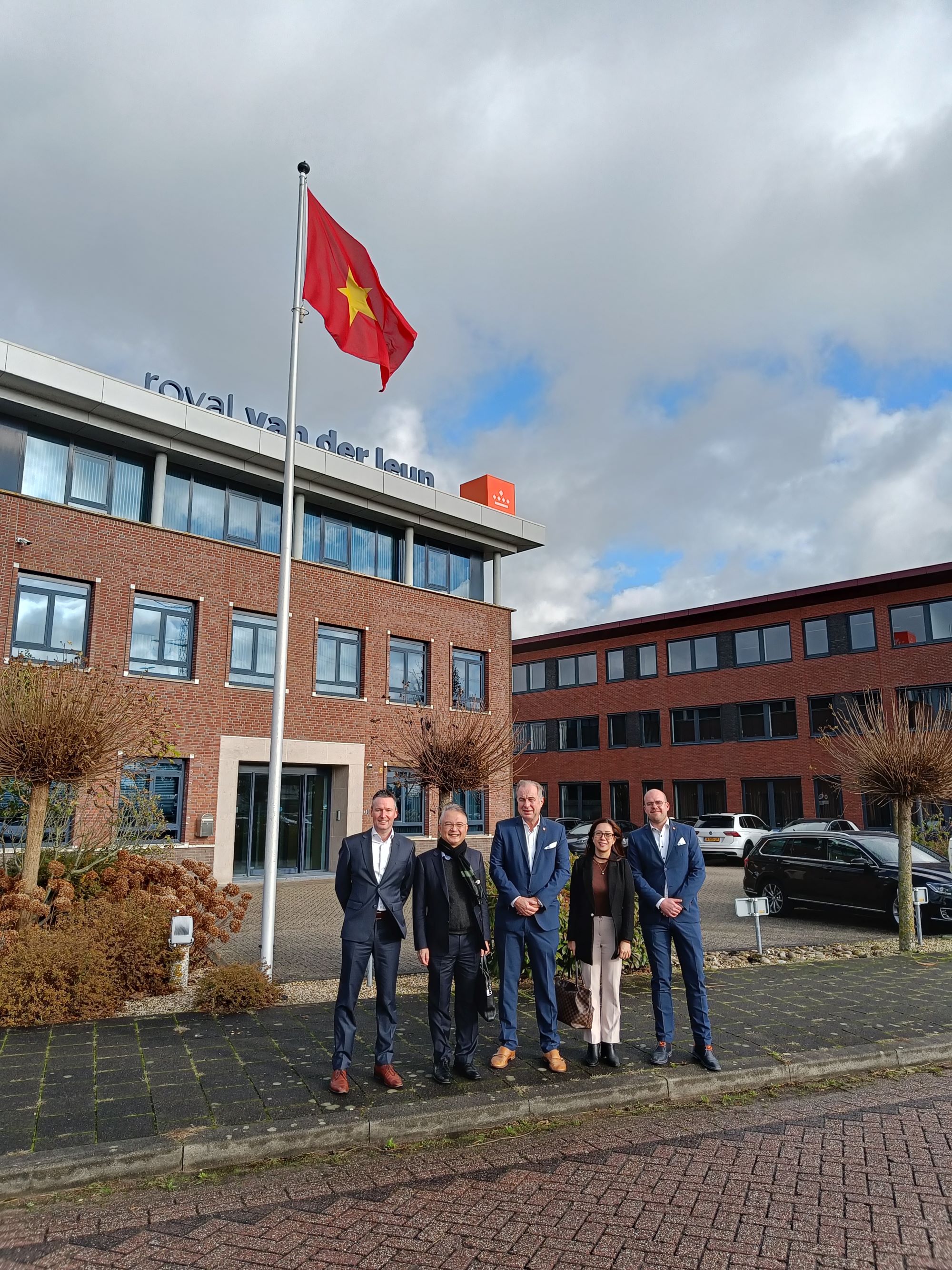 delegatie-vietnamese-ambassade-poseert-bij-vietnamese-vlag-hoofdkantoor-royal-van-der-leun